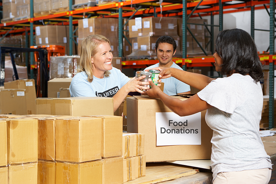 Non Profit Volunteers Collecting Food Donations In Warehouse