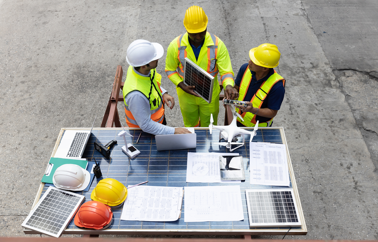 Employees at a Portland manufacturing facility have a discussion next to a work table filled with papers and equipment.